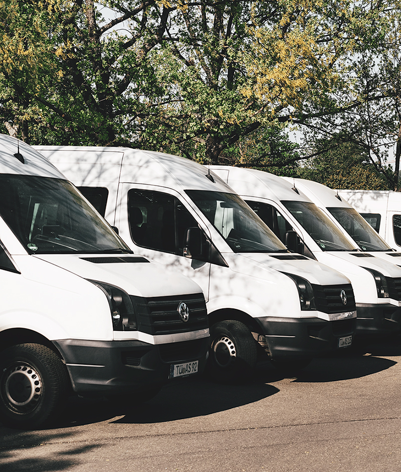 white commercial fleet vehicles parked in a line